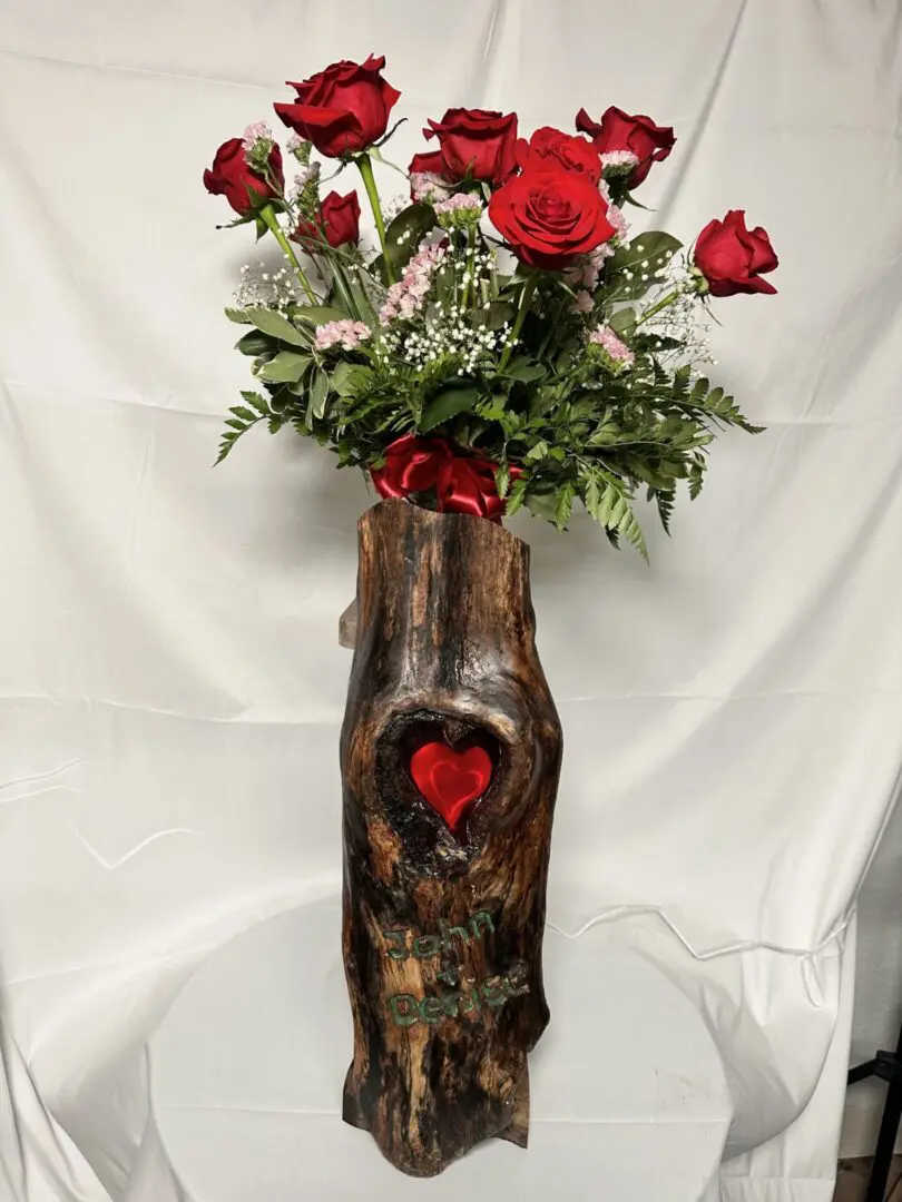 Red roses in carved wooden heart vase