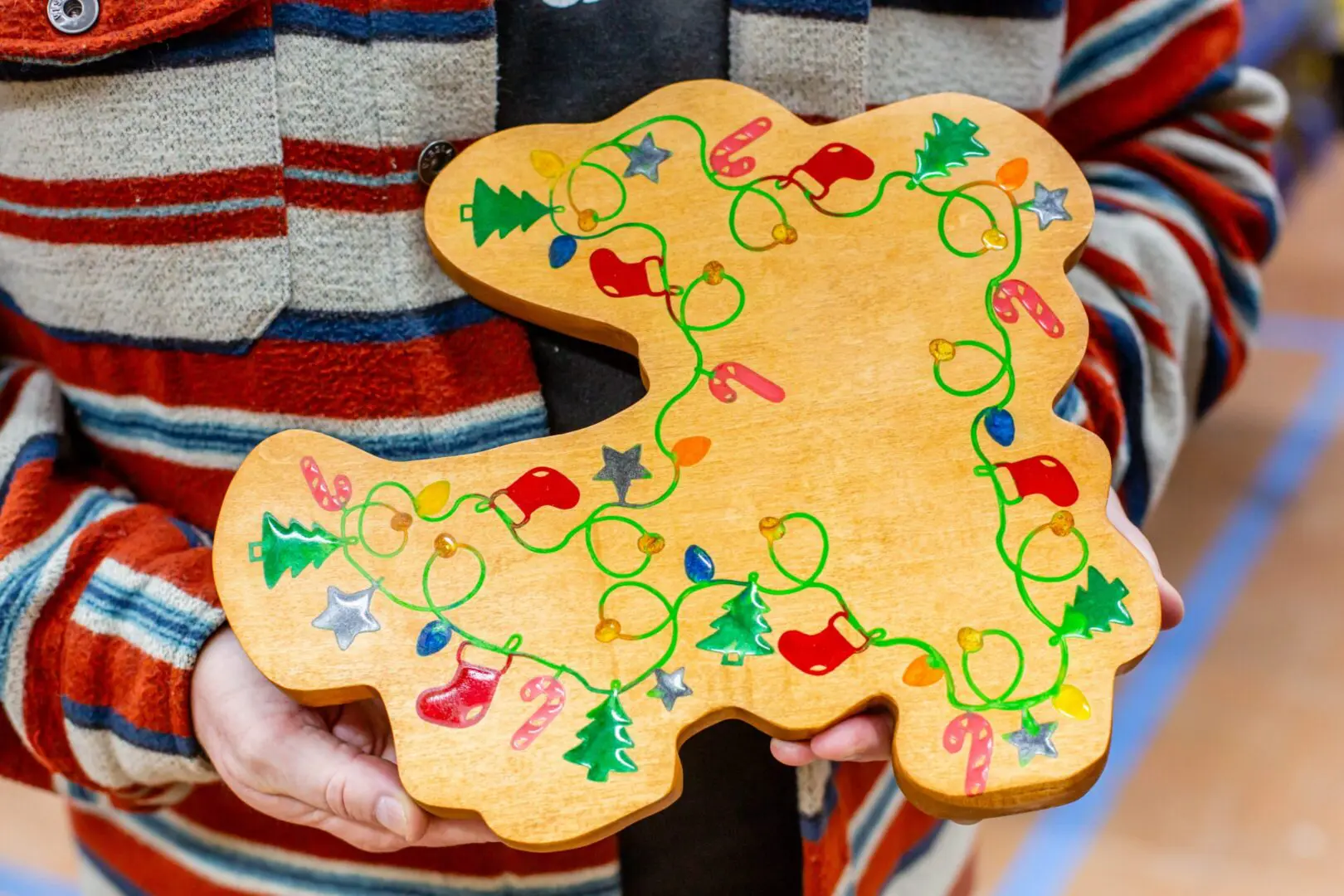 Child holding decorated wooden gingerbread-shaped board